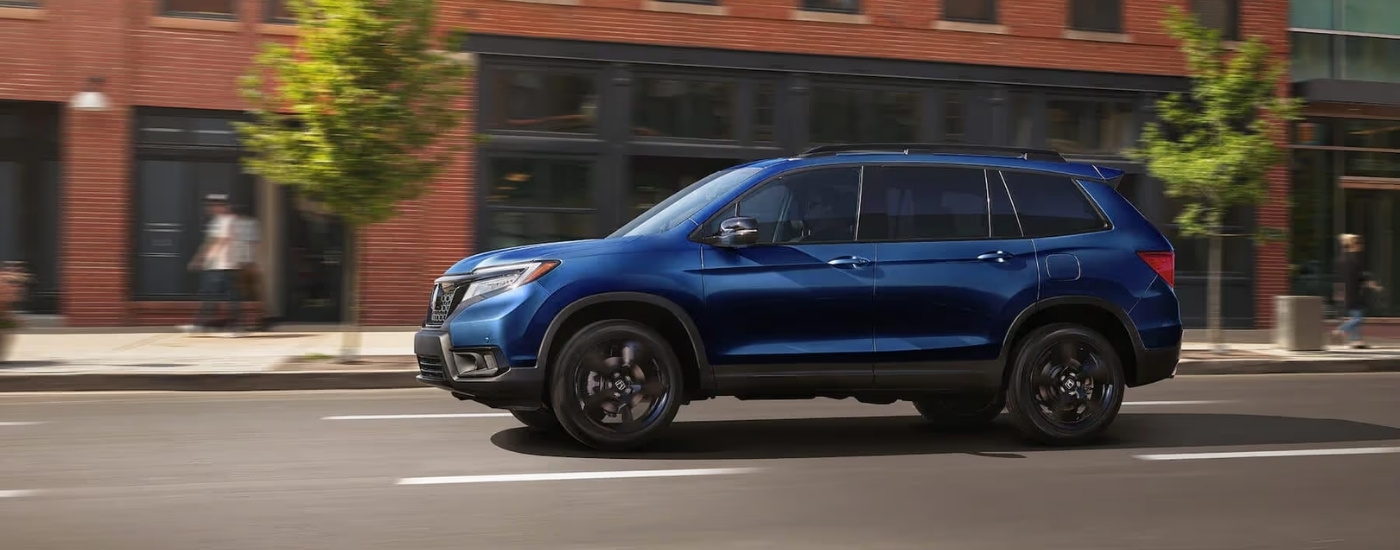 Blue 2021 Honda Passport Elite is driving on a city street