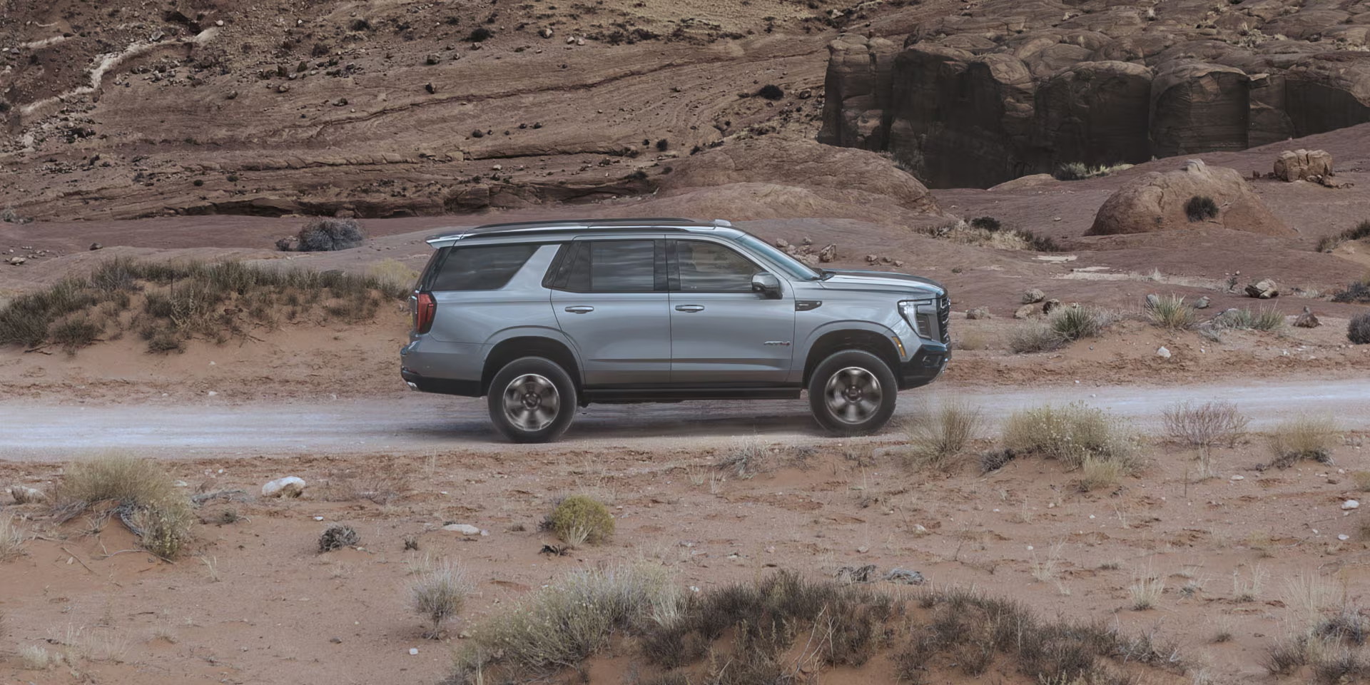 Silver GMC Yukon driving on a desert dirt road