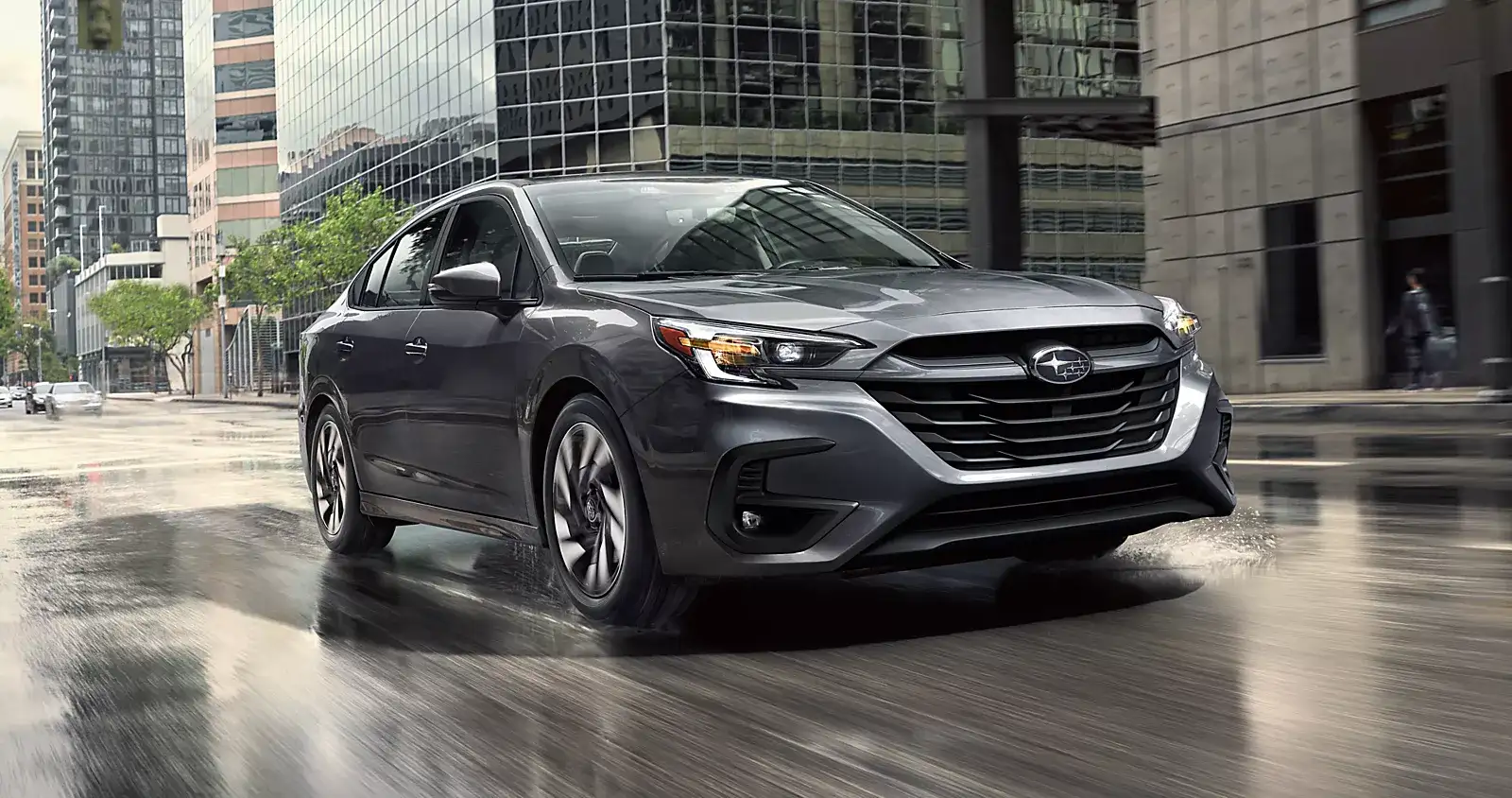 Gray Subaru Legacy driving on a wet city street