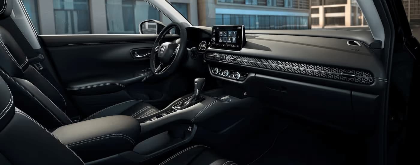 The black interior of a 2023 Honda HR-V EX-L shows the center console and dashboard.