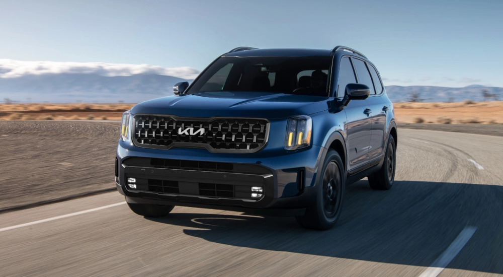 Dark blue 2025 Kia Telluride for sale driving on an open highway