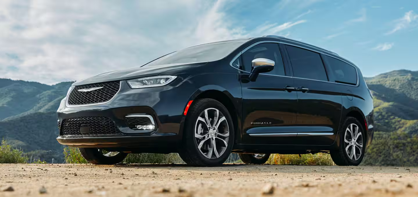 A black chrysler pacifica parked on a dirt road.