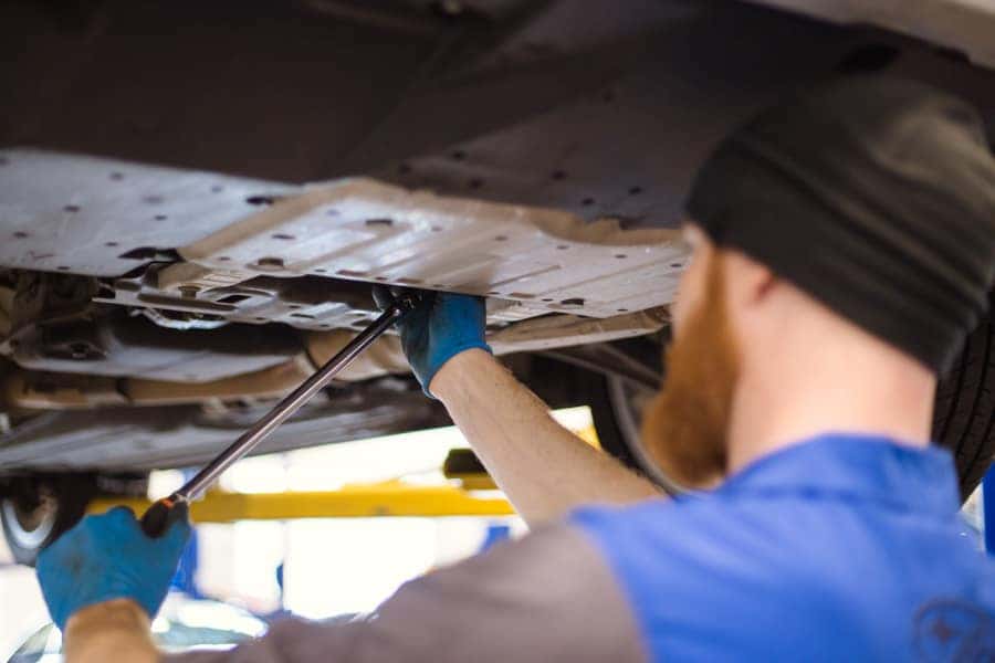 Subaru technician tightening a part underneath a vehicle