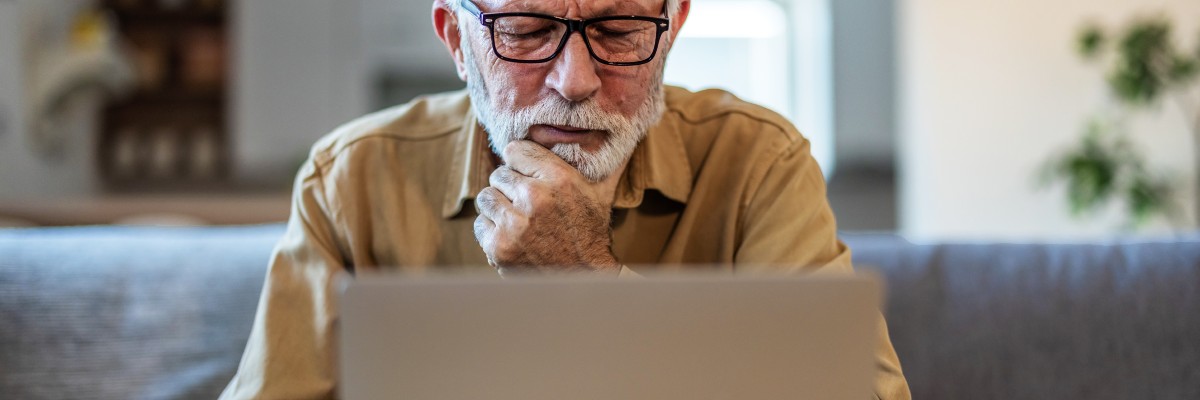 Elderly Man Looking at Laptop Screen & Thinking