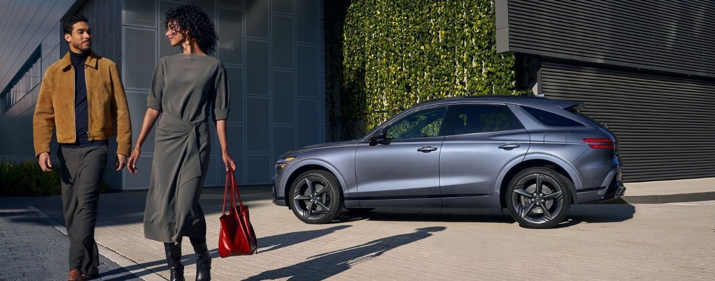 Couple walking near a grey 2026 Genesis GV70