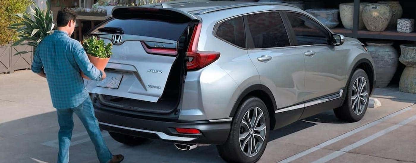A man is shown opening the lift gate of a silver 2021 Honda CR-V.