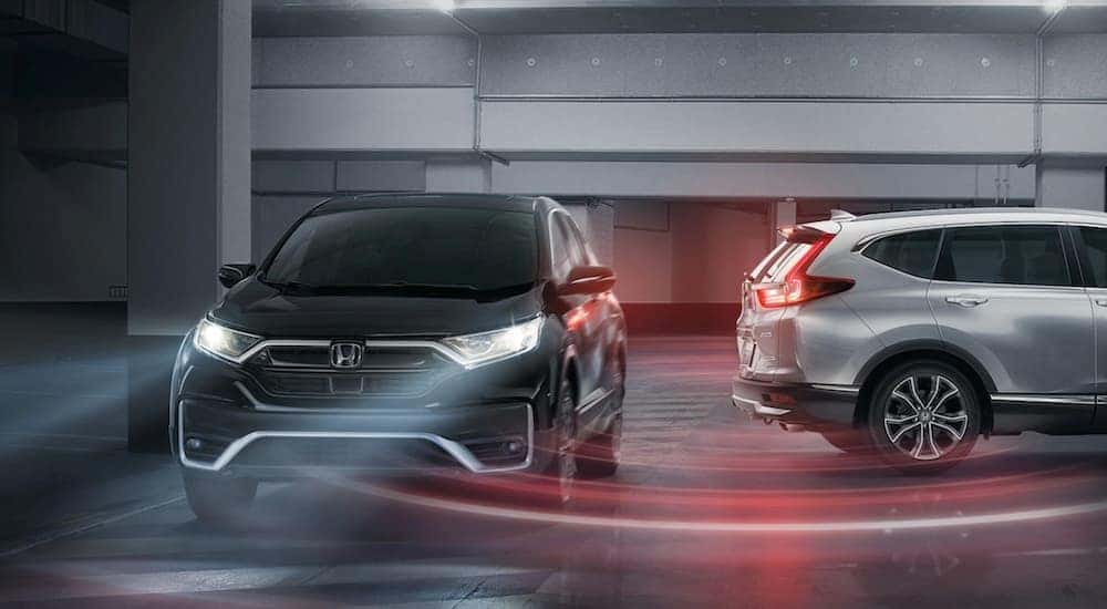 A black and a silver 2022 Honda CR-V touring are shown in a parking garage.