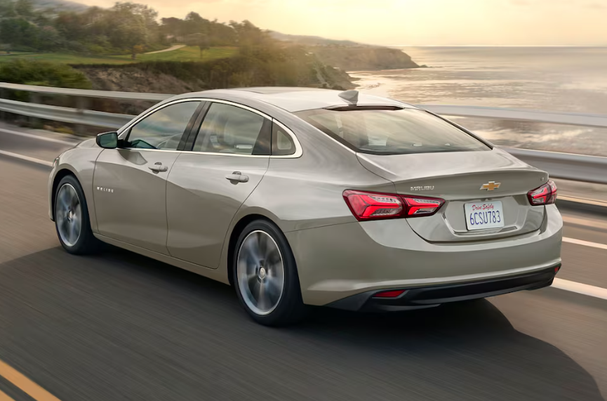 The 2025 Chevrolet Malibu is driving down a coastal highway.