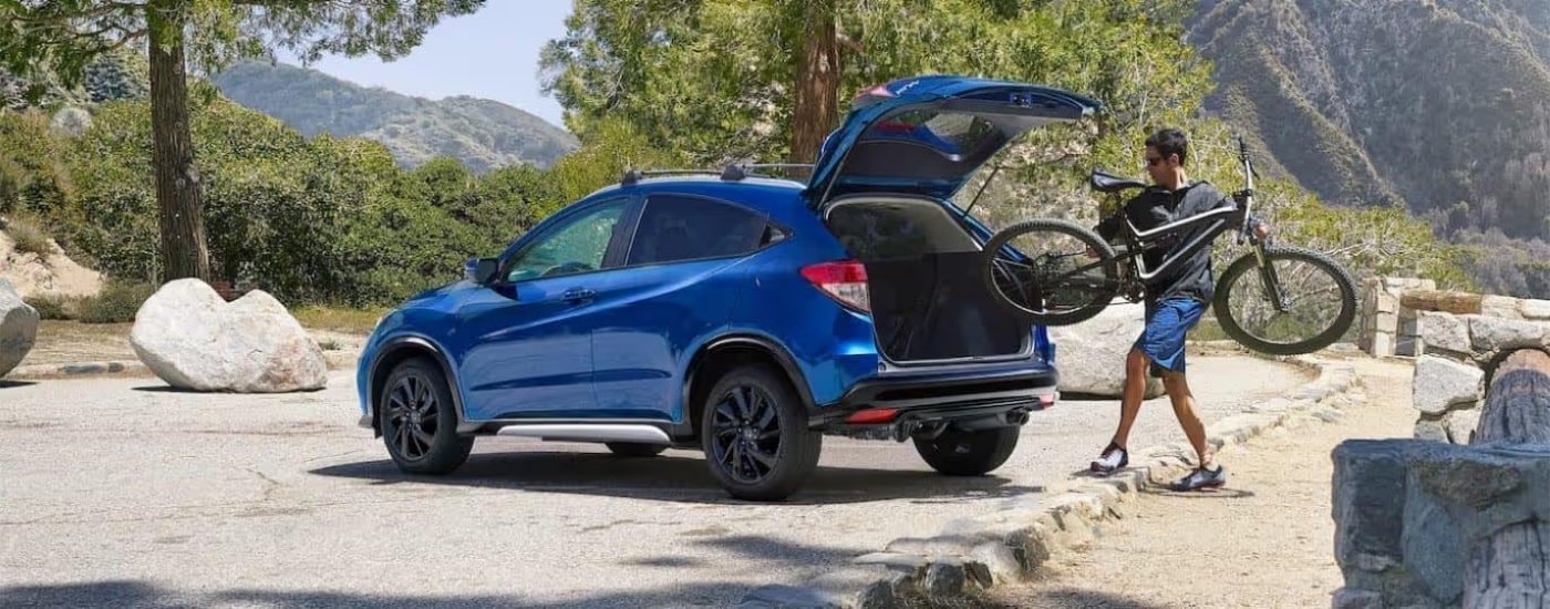 Man loading a bike into the cargo space of a blue 2022 Honda HR-V