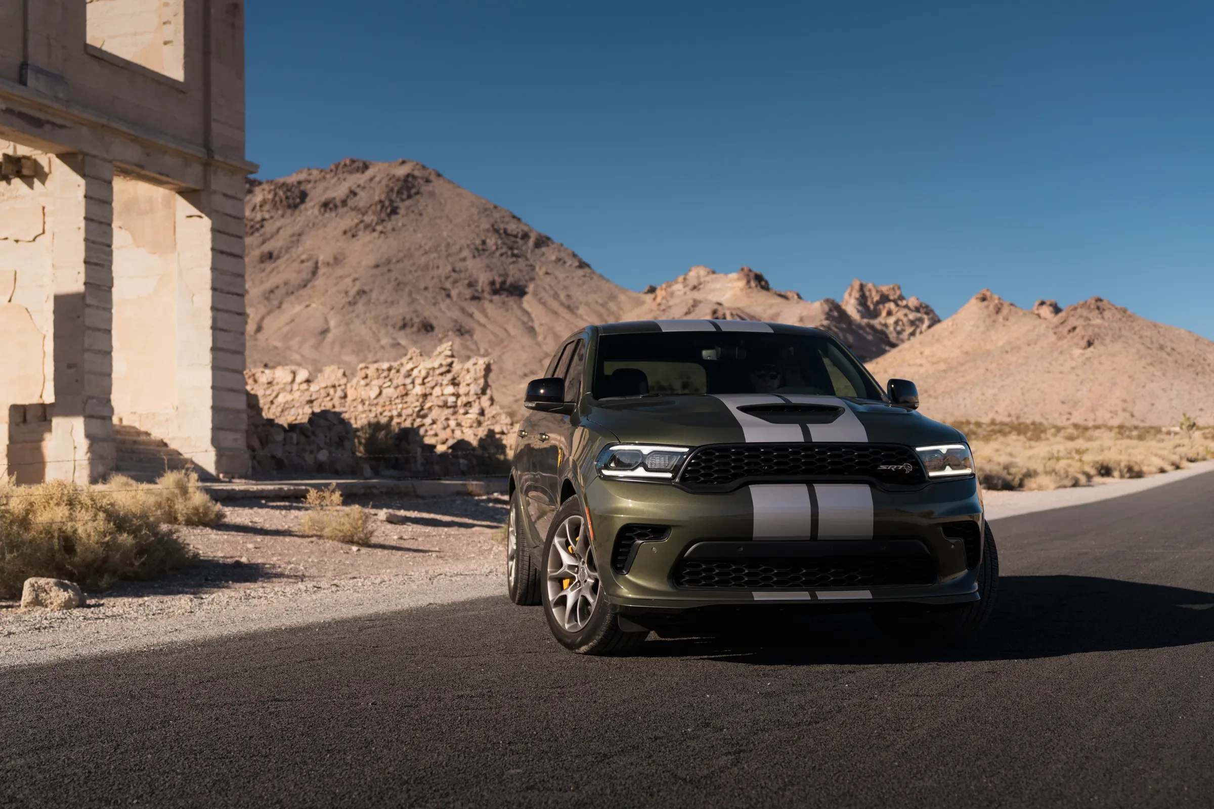 2026 Dark green Dodge Durango SRT with silver racing stripes parked near desert ruins and rocky mountains