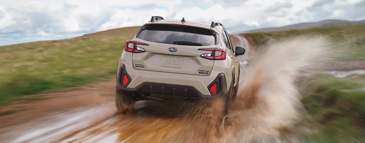 Tan 2026 Subaru Crosstrek Hybrid Limited driving on a muddy trail