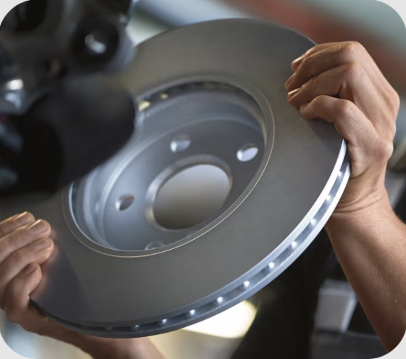 Closeup view of hands holding a circular piece  of metal with the background blurred out.