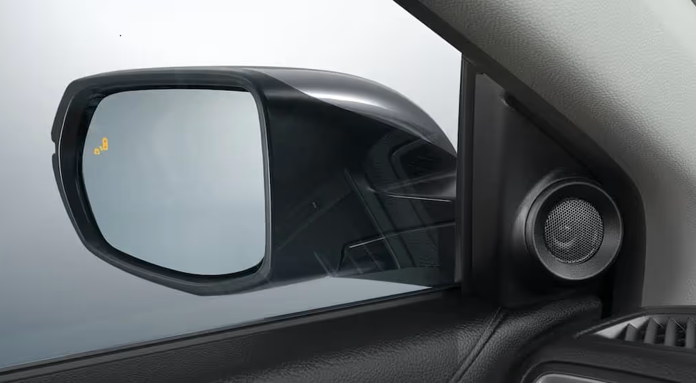 A close up shows the blind spot monitoring icon on the mirror of a 2021 Honda CR-V Touring.