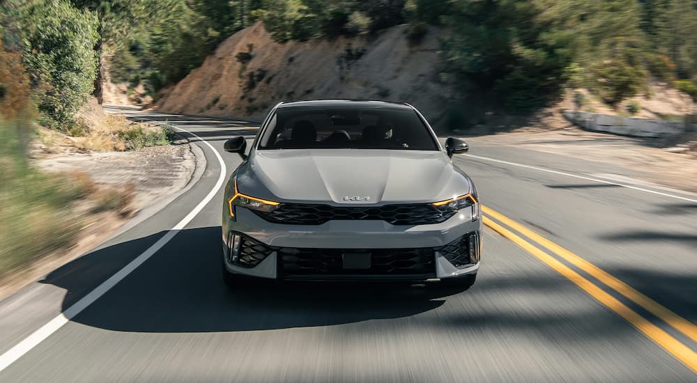 Grey 2026 Kia K5 driving on a winding road