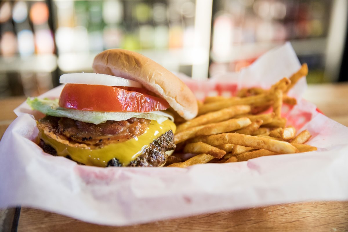 cheeseburger with bacon, lettuce, tomato, and onion; served with a side of fries in a basket