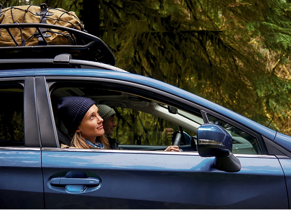 Person looking out passenger front window of a Blue Subaru.