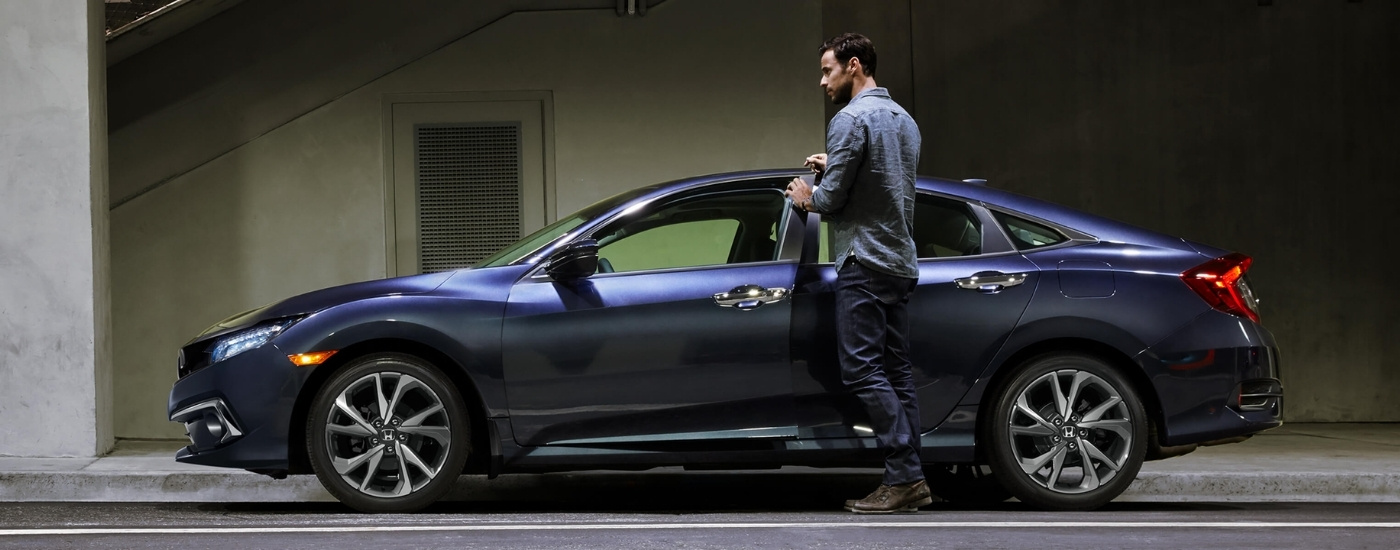 Person opening a door on a blue 2021 Honda Civic Sport