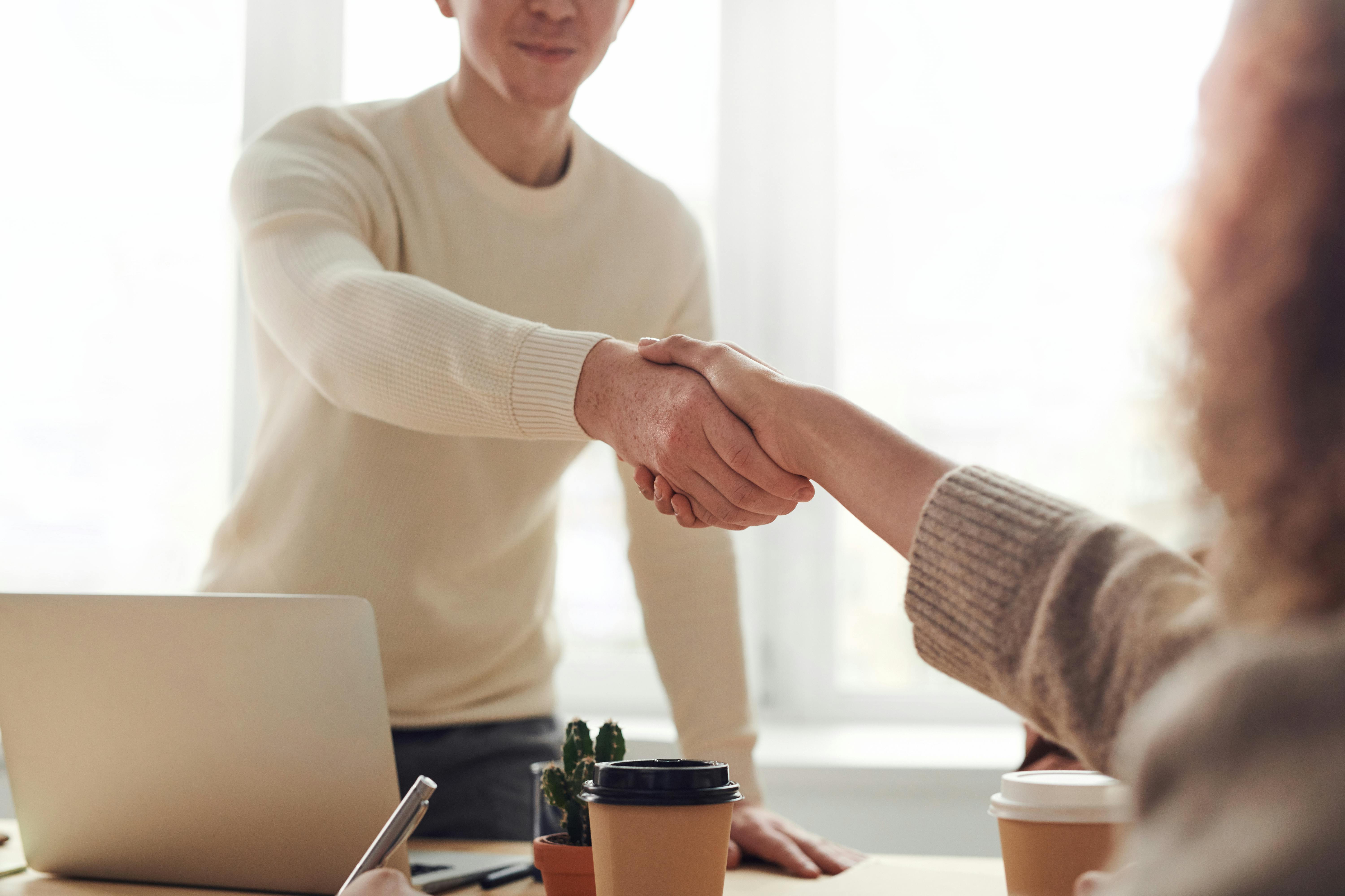 Customer and sales consultant shaking hands inside a dealership