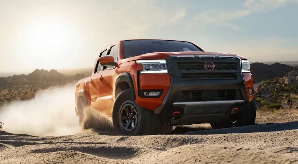 Orange 2026 Nissan Frontier driving off-road.