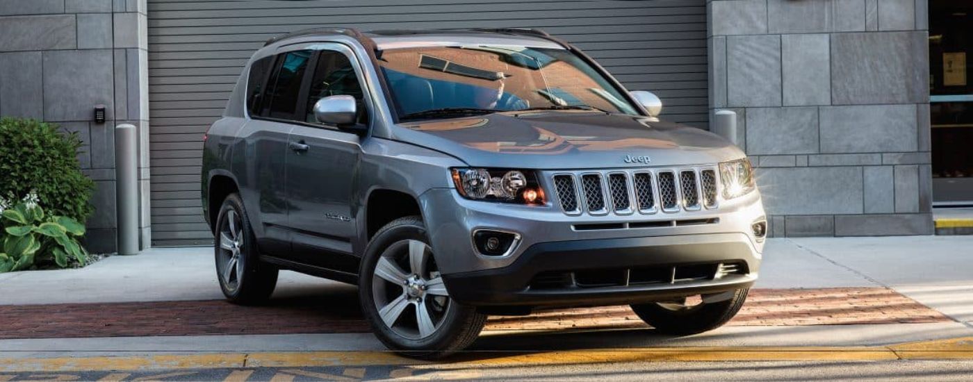 A silver 2017 Jeep Compass High Altitude is shown parked in front of a building.