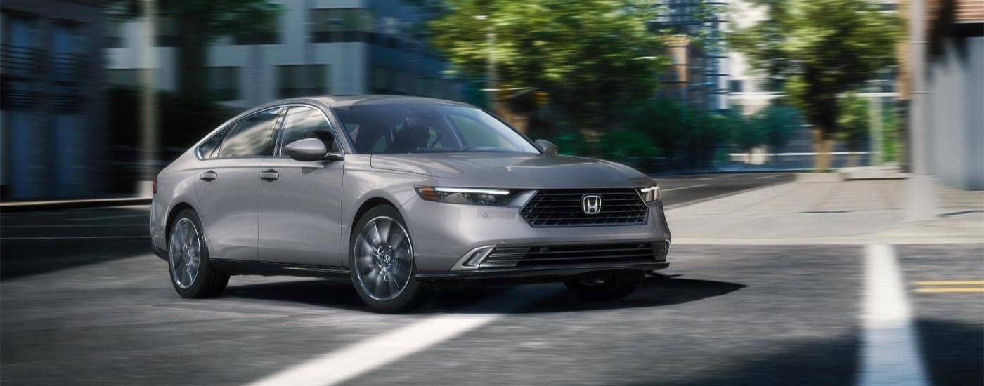 Gray 2025 Honda Accord Hybrid driving on a city street