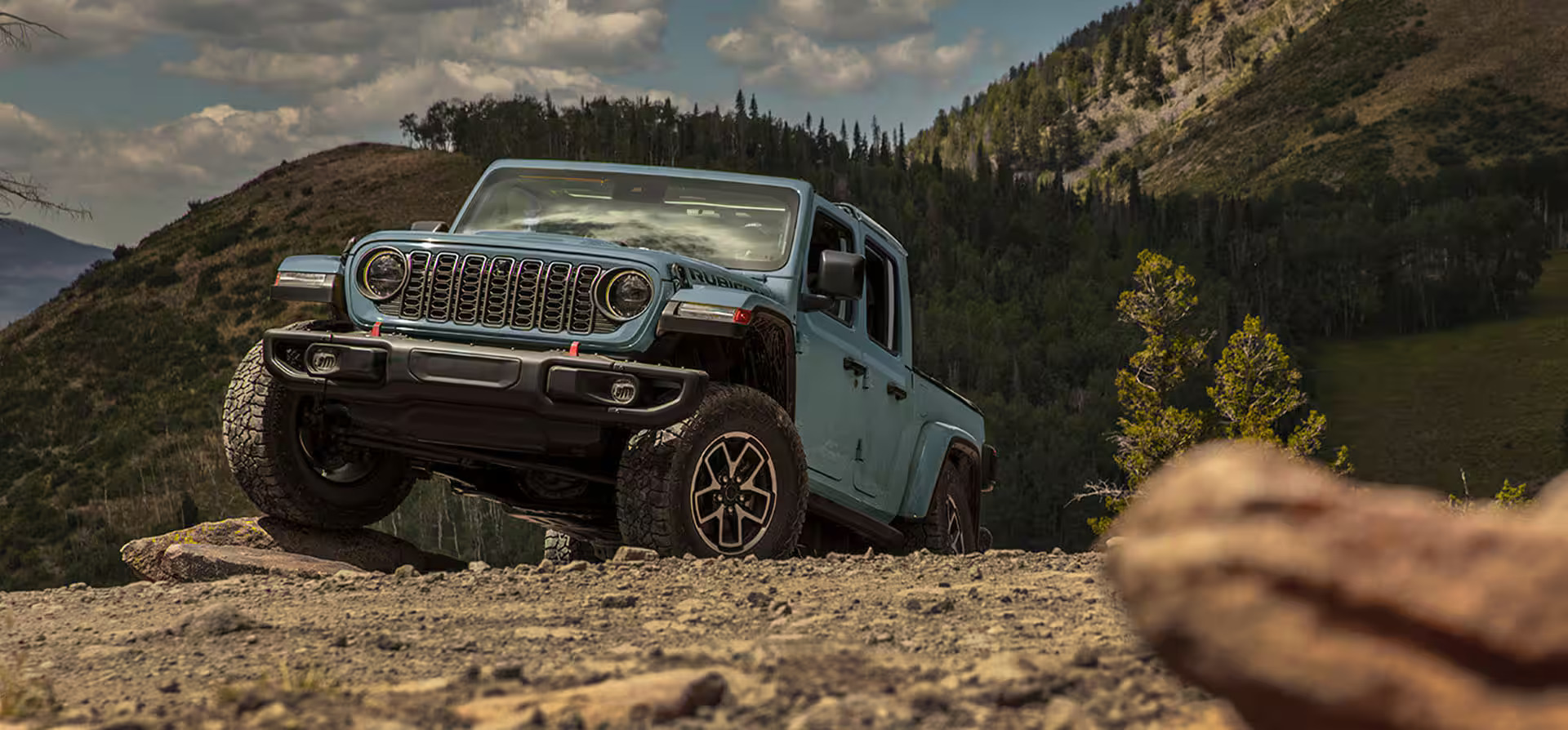 A blue jeep driving up a hill.