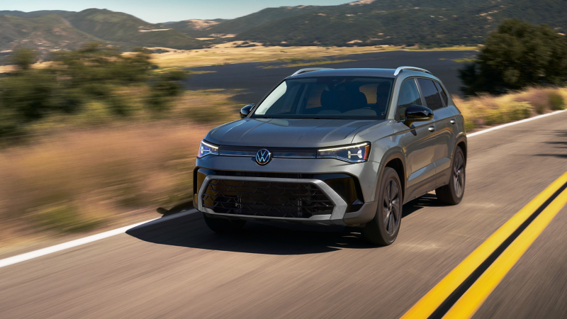 2027 Volkswagen Taos in gray driving on a mountain road, front three-quarter view