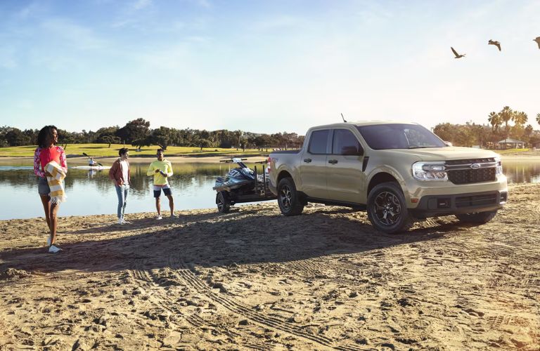 Tan 2024 Ford Maverick Towing a Trailer of Jet Skis at the Beach