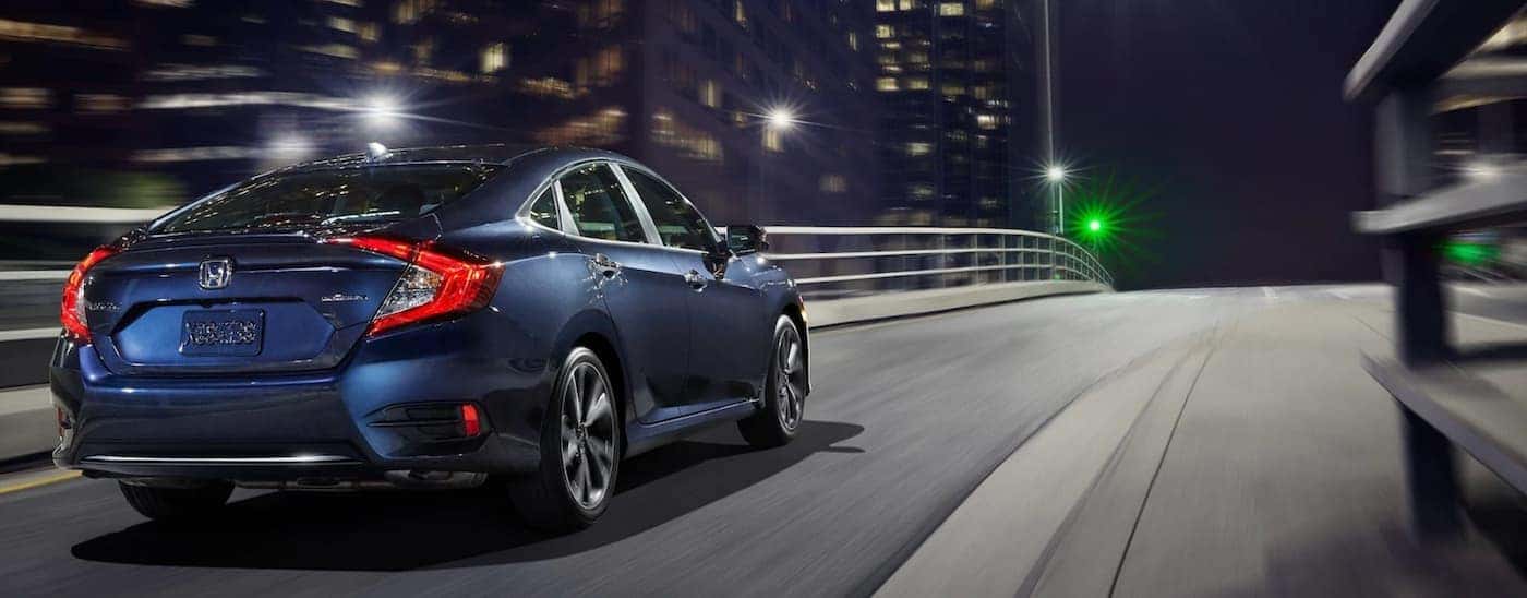 A blue 2021 Honda Civic EX is driving on a city street after leaving a Honda dealer near Brockport.