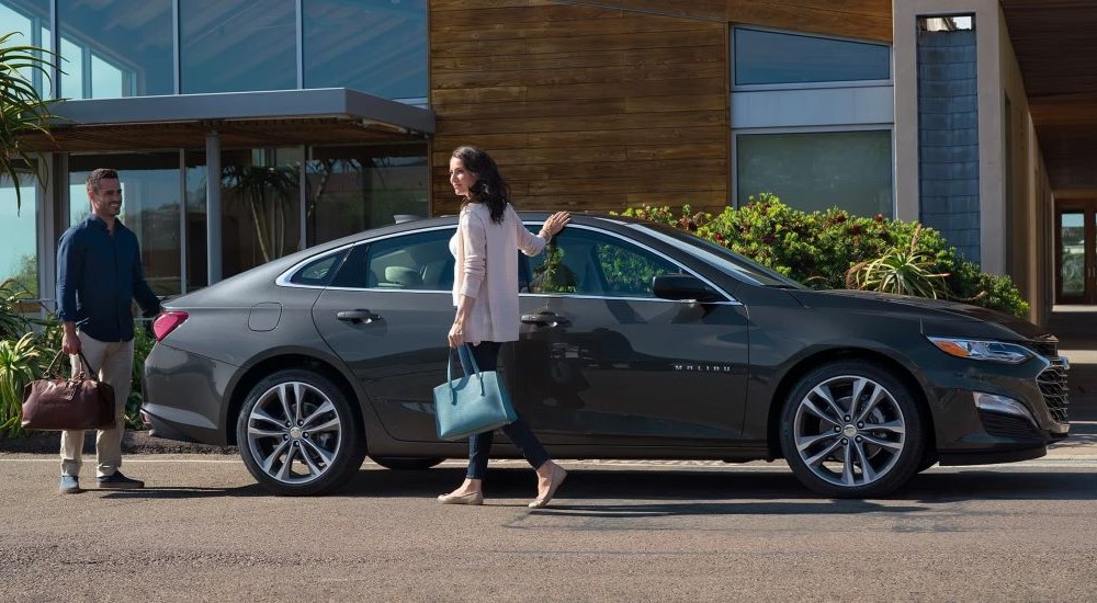 People walking near a grey 2023 Chevy Malibu