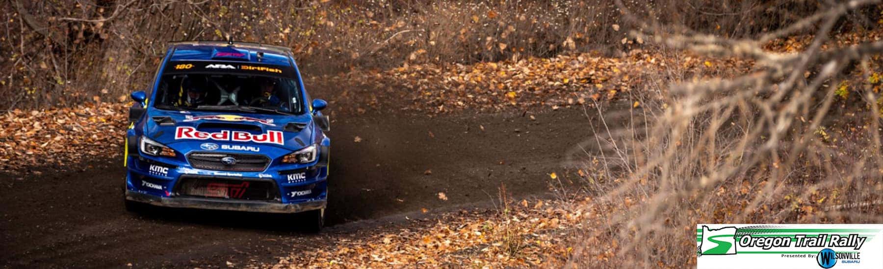 Blue Subaru rally car racing on a forest stage