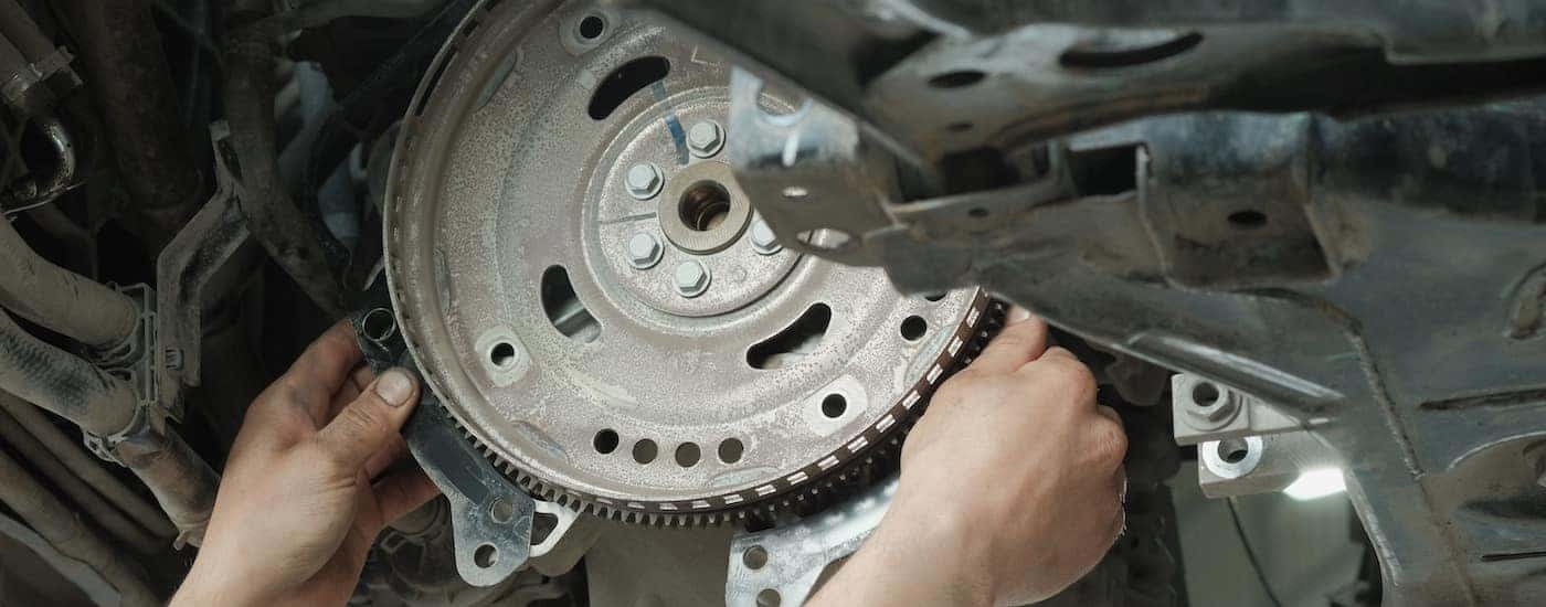 Close-up of a mechanic inspecting a car's torque converter at a transmission shop near Greece.