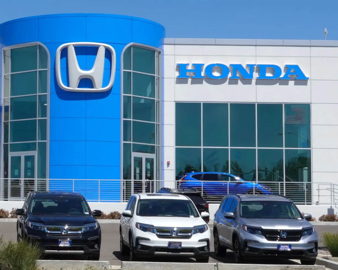 Honda dealership exterior with multiple SUVs displayed in front of the showroom on a clear day.