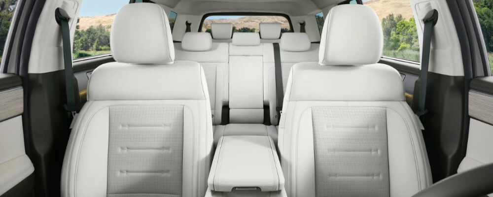 2024 Hyundai Santa Fe interior showcasing spacious three-row seating with modern white upholstery and panoramic views through windows.