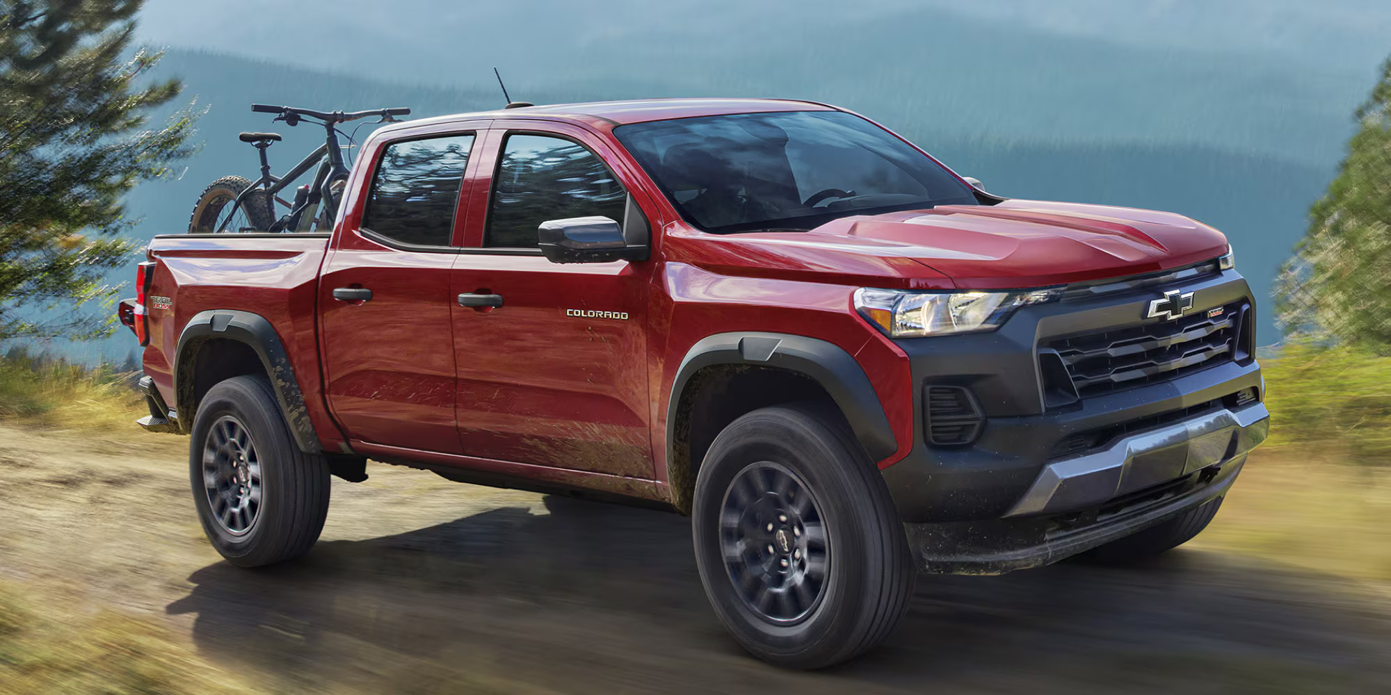 A red colorado driving on a dirt road.