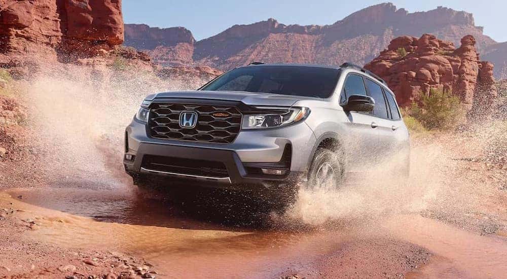 A popular Honda Passport for sale, a silver 2024 Honda Passport TrailSport, is shown driving off-road.