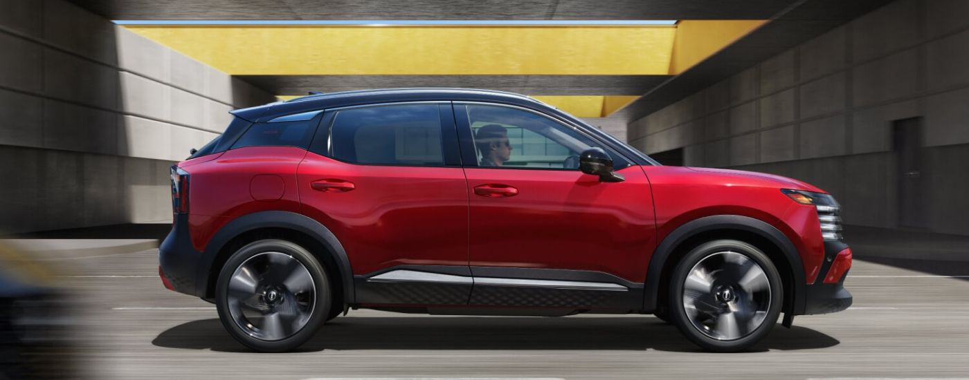 Side view of a red 2026 Nissan Kicks driving.