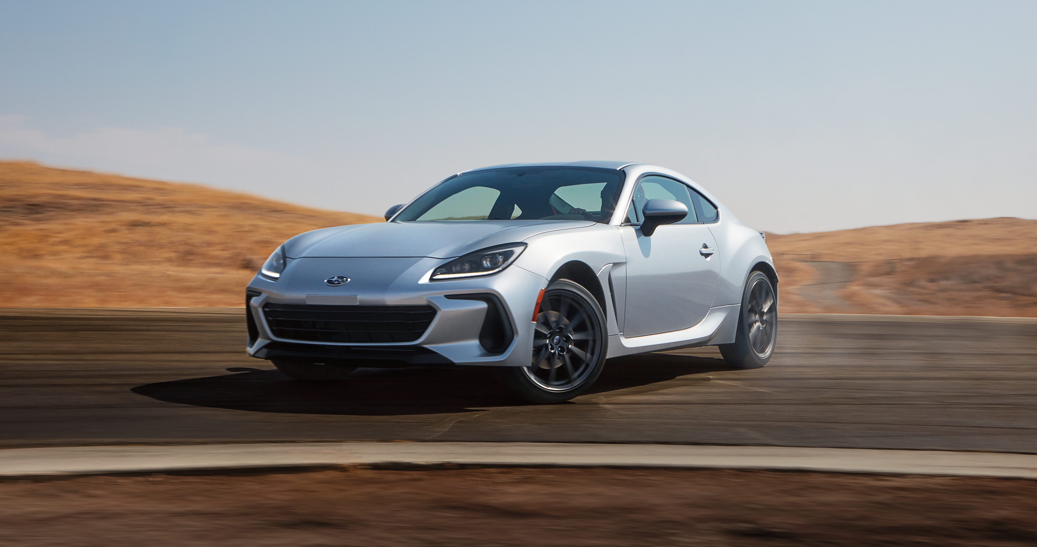 25_BRZ_hero_gallery_1.png / A 2025 Subaru BRZ sports coupe drifts around a corner on a racetrack.