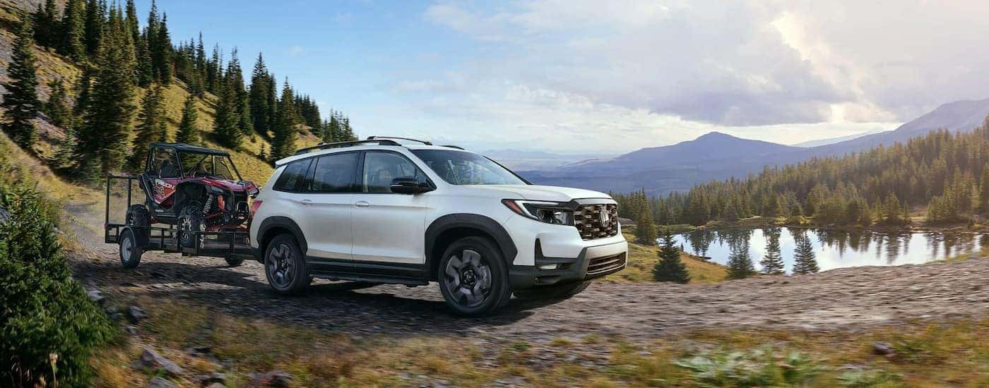 A white 2022 Honda Passport Elite is shown driving near a body of water after leaving a Rochester Honda dealer