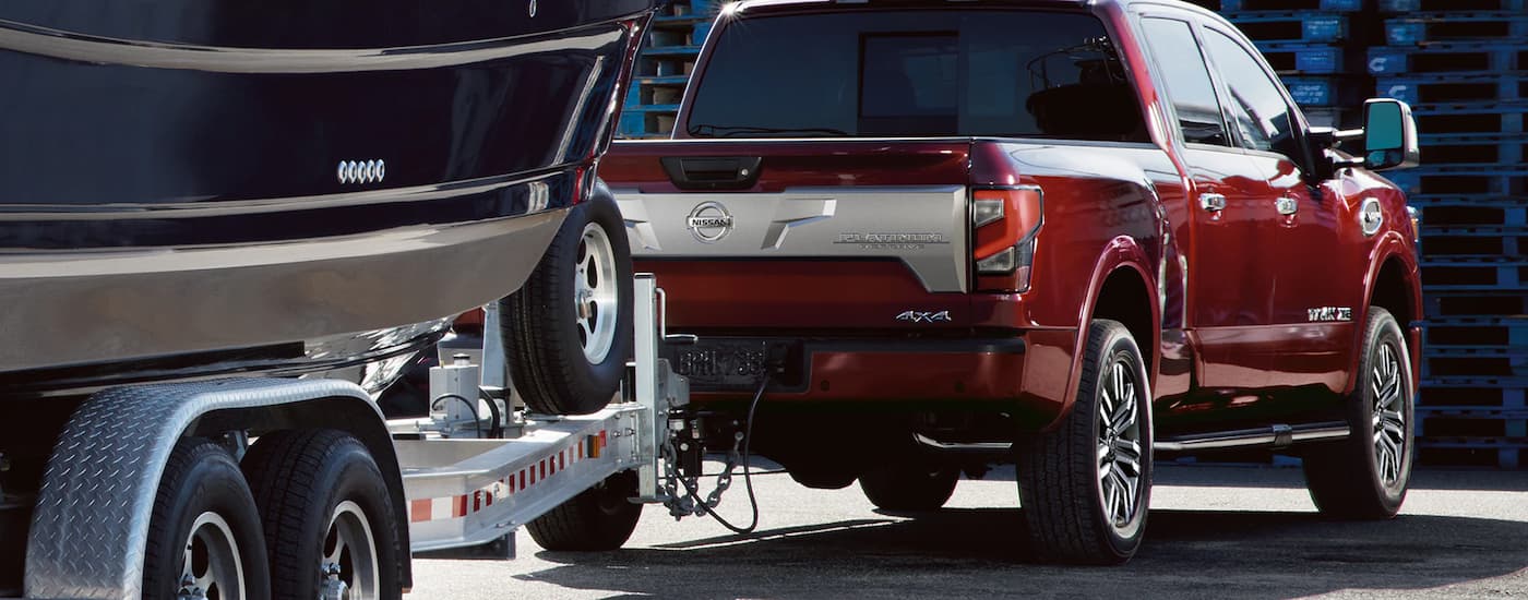 A red 2022 Nissan Titan Platinum is towing a boat.
