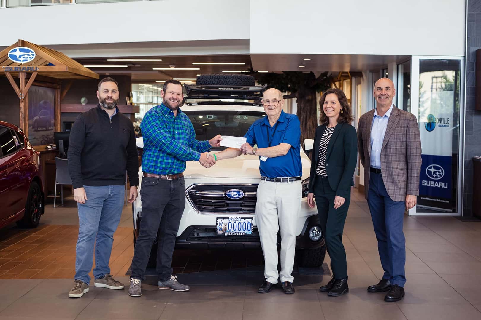 Wilsonville Subaru team presenting a donation check in the showroom