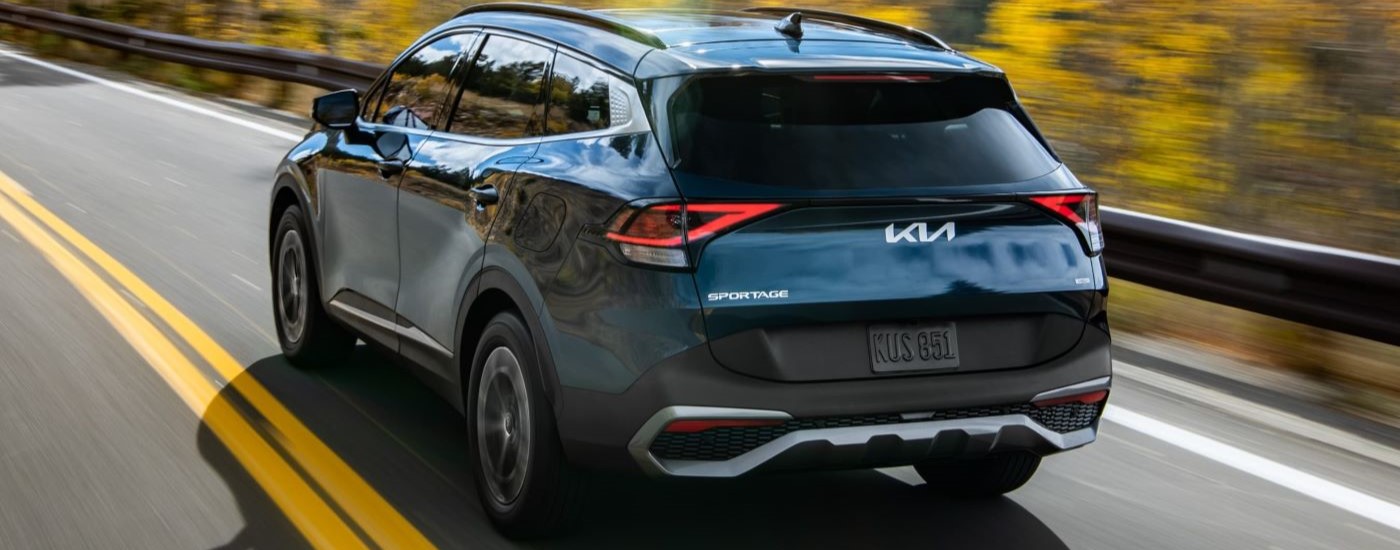 lack 2023 Kia Sportage Hybrid driving down a road