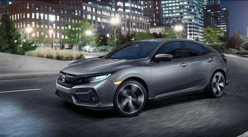 A silver 2021 Honda Civic Hatchback is driving through the city after leaving the Honda dealer in Rochester.