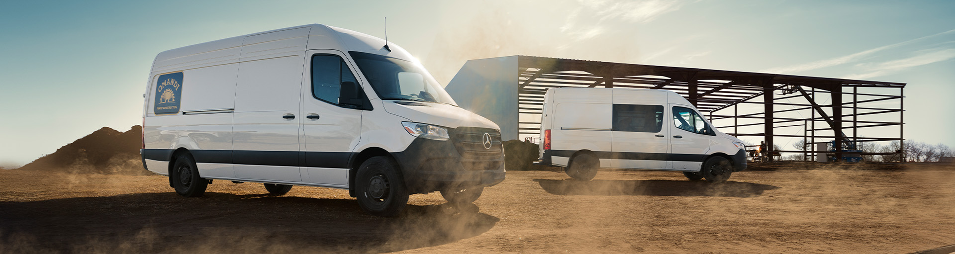 Two Mercedes-Benz Sprinter Cargo Vans parked near a building undergoing construction.