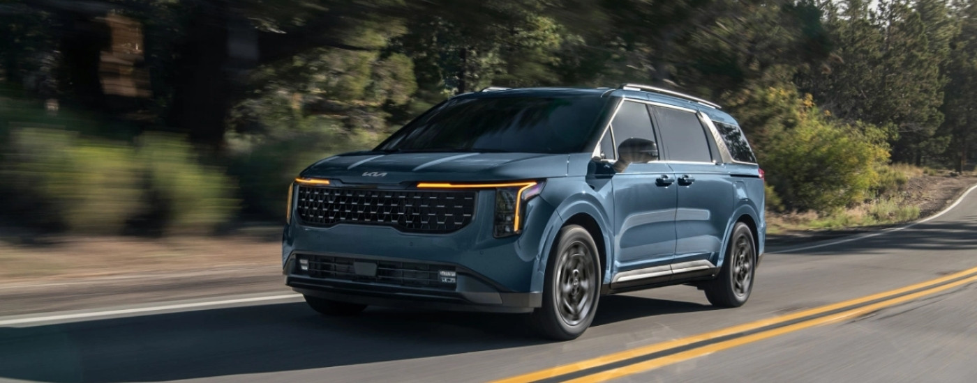 Blue 2025 Kia Carnival driving to a Kia dealer near Edina