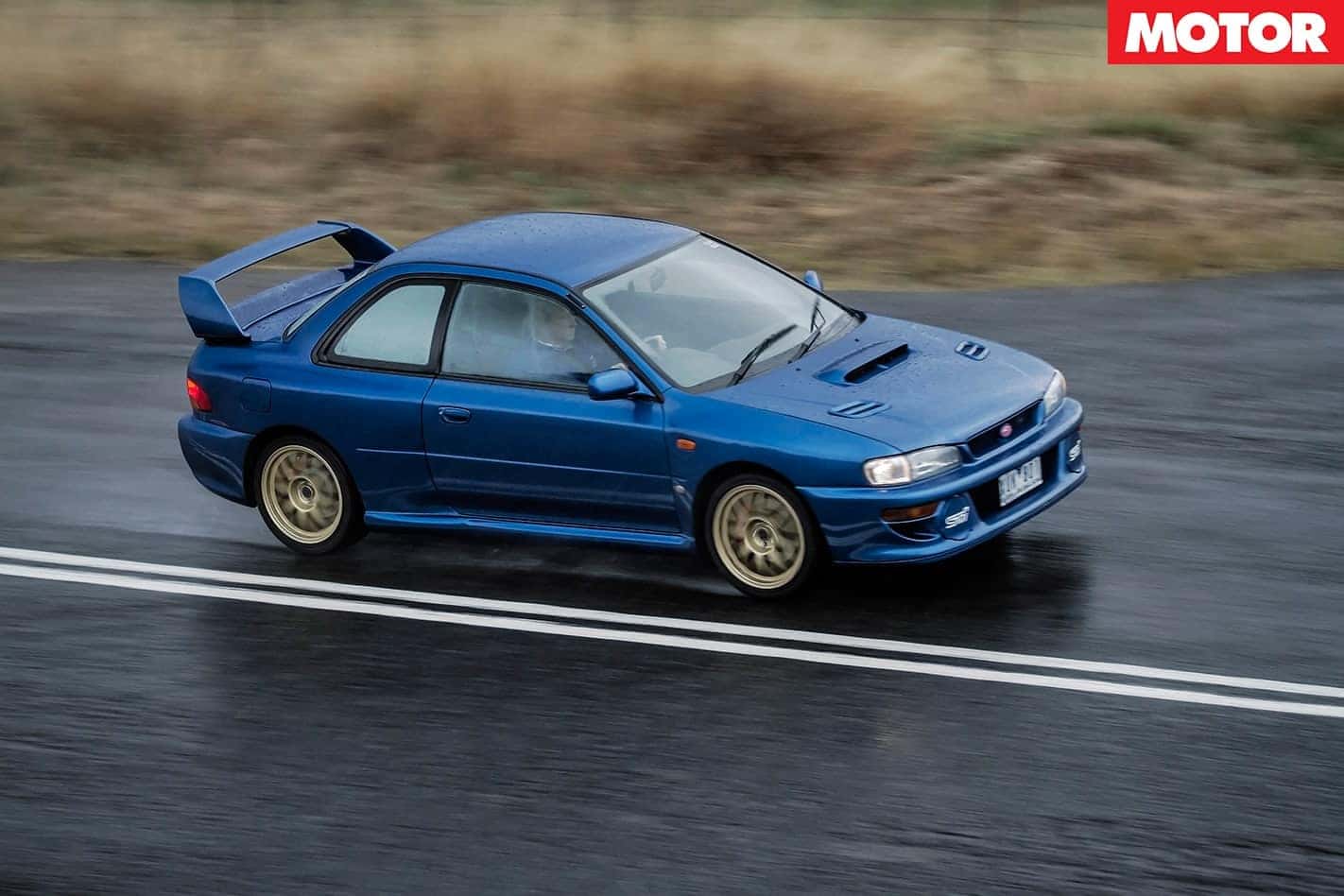Classic blue Subaru Impreza coupe with gold wheels