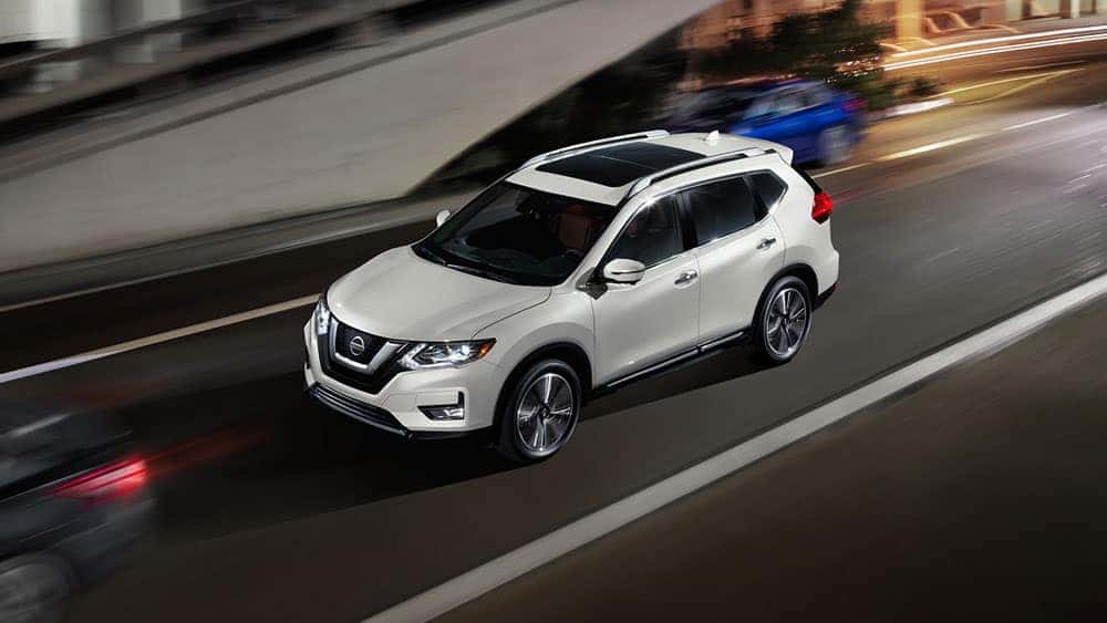 White 2017 Nissan Rogue driving on a city street at night