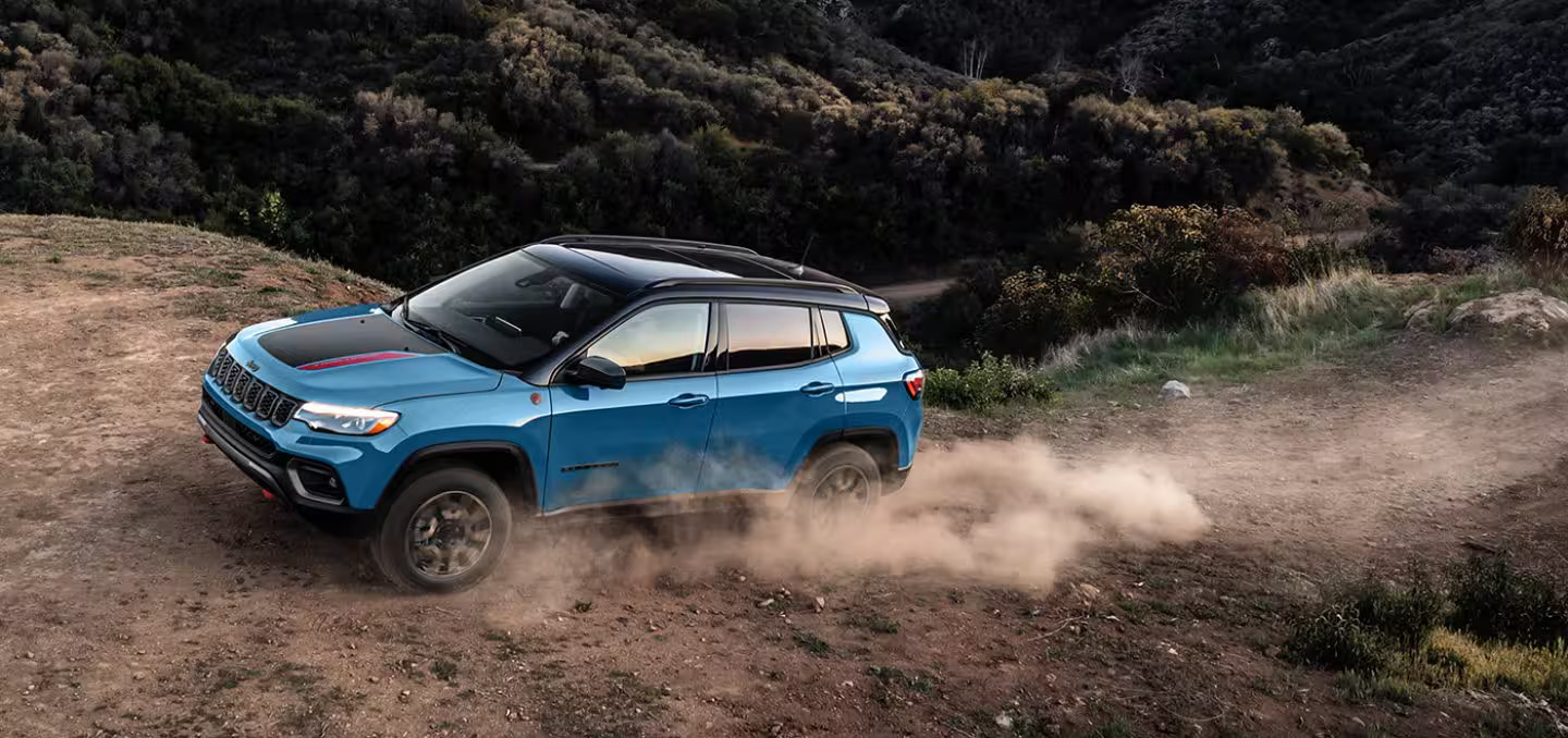 A blue compass driving on a dirt road.