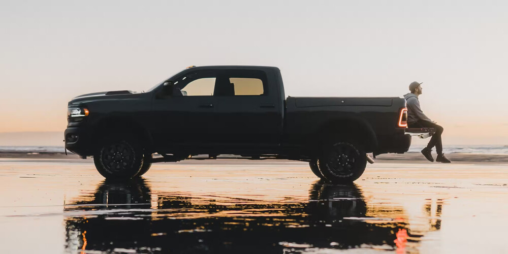2024 RAM 2500 with man relaxing on tailgate near dusk