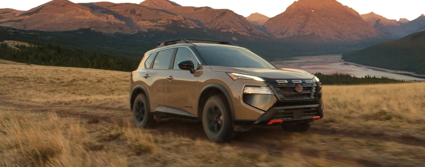 Brown 2026 Nissan Rogue driving along a trai